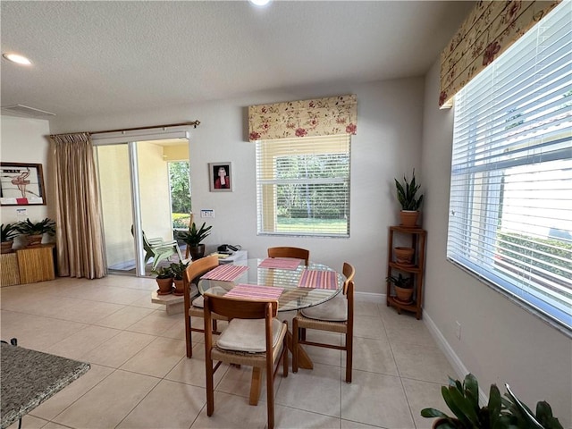 dining space featuring light tile patterned floors, baseboards, and a textured ceiling