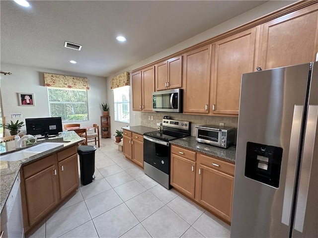 kitchen featuring visible vents, a sink, stainless steel appliances, a toaster, and decorative backsplash