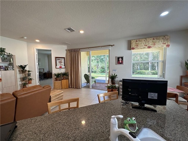 living area featuring light tile patterned flooring, visible vents, recessed lighting, and a textured ceiling