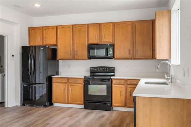 kitchen with sink, black appliances, and light hardwood / wood-style flooring