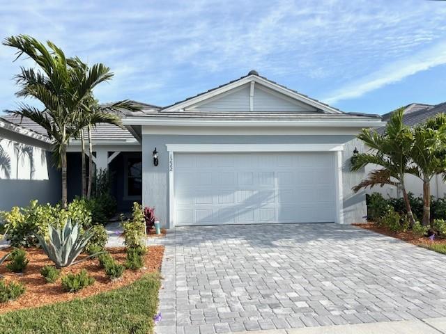ranch-style home with decorative driveway, a garage, and stucco siding
