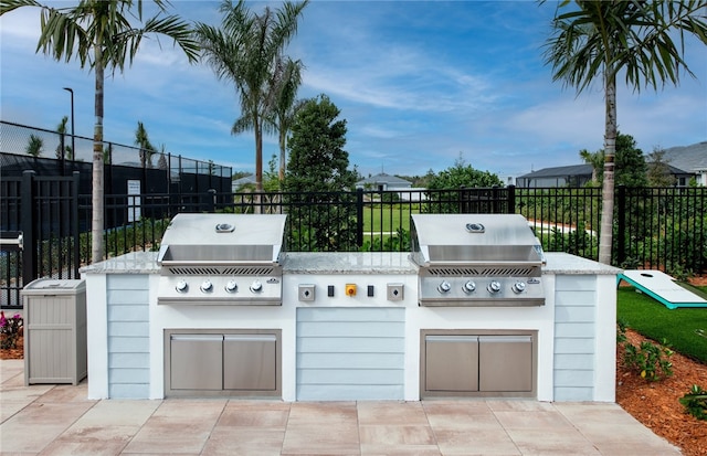 view of patio featuring a grill, an outdoor kitchen, and fence
