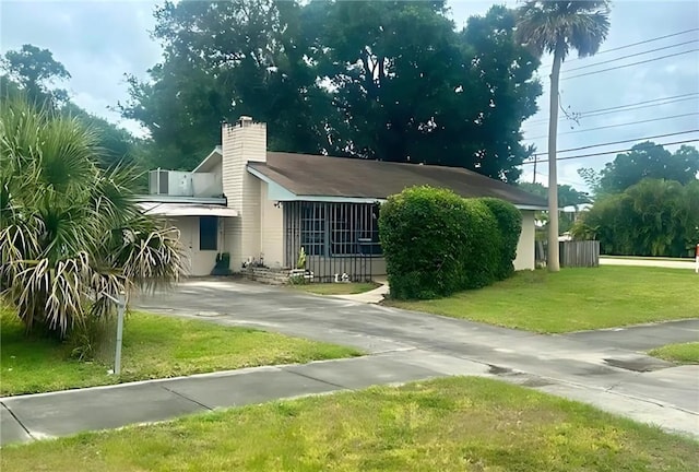 1606 34th Ave, Vero Beach, FL 32960 - view of home's exterior with a yard, concrete driveway, and a chimney