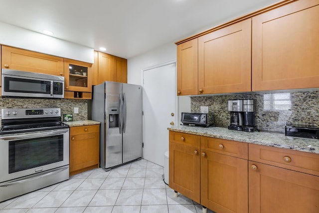 kitchen featuring light tile patterned floors, light stone countertops, backsplash, and appliances with stainless steel finishes