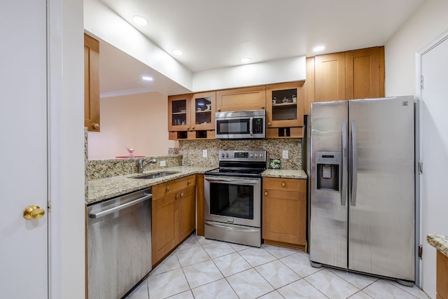 kitchen featuring light stone counters, sink, light tile patterned floors, and stainless steel appliances