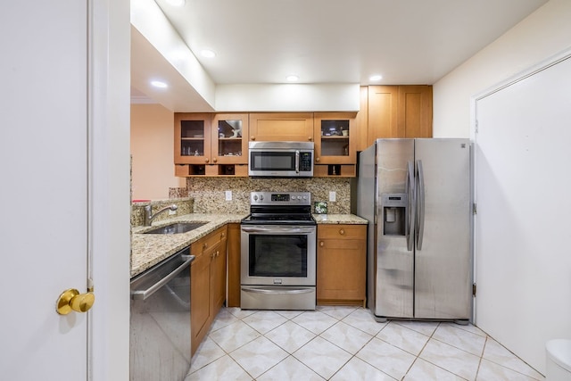 kitchen featuring light stone counters, sink, stainless steel appliances, and tasteful backsplash