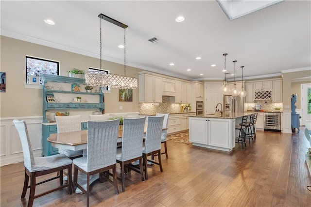 5417 Antigua Cir, Vero Beach, FL 32967 - dining area with wine cooler, ornamental molding, recessed lighting, dark wood-style floors, and wainscoting