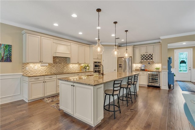 5417 Antigua Cir, Vero Beach, FL 32967 - kitchen featuring appliances with stainless steel finishes, beverage cooler, dark wood-style flooring, cream cabinetry, and crown molding