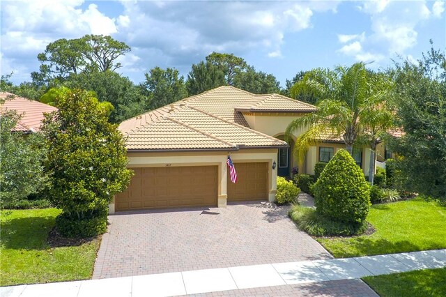 5417 Antigua Cir, Vero Beach, FL 32967 - mediterranean / spanish house featuring an attached garage, decorative driveway, a tiled roof, a front yard, and stucco siding