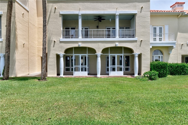 back of property featuring a yard, ceiling fan, and a balcony