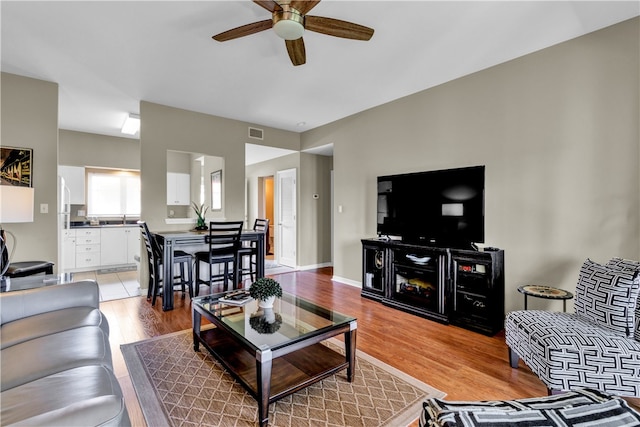 living room with ceiling fan and light hardwood / wood-style flooring