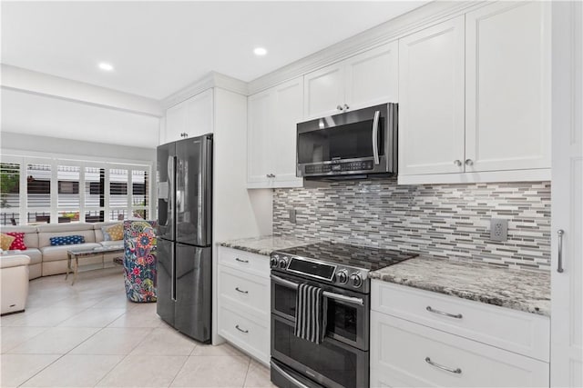 kitchen featuring tasteful backsplash, white cabinetry, light stone counters, and appliances with stainless steel finishes