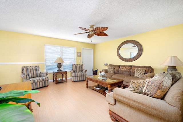 living room featuring wood-type flooring, ceiling fan, and a textured ceiling