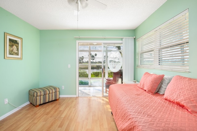 bedroom featuring ceiling fan, access to exterior, a textured ceiling, and light hardwood / wood-style flooring