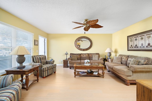 living room featuring ceiling fan, a textured ceiling, and light hardwood / wood-style floors