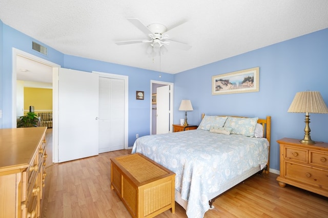 bedroom featuring ceiling fan, a textured ceiling, a closet, and light wood-type flooring