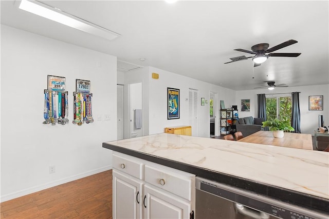 kitchen featuring baseboards, white cabinets, dishwasher, light stone counters, and wood finished floors