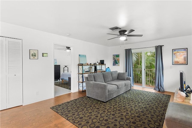 living area with a ceiling fan, visible vents, and wood finished floors