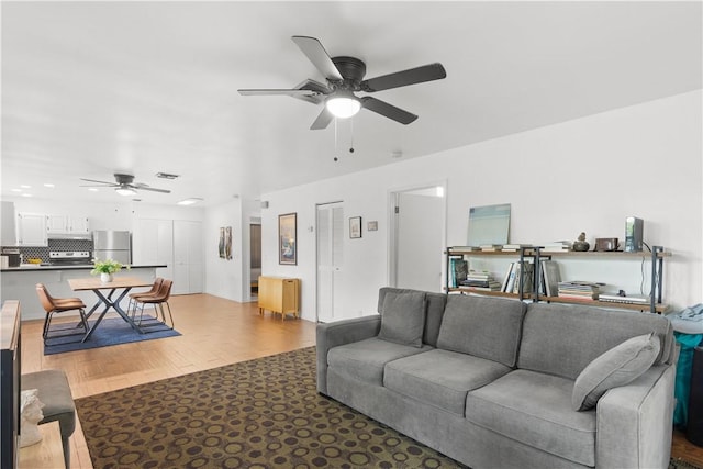 living area with a ceiling fan, visible vents, and light wood-style flooring