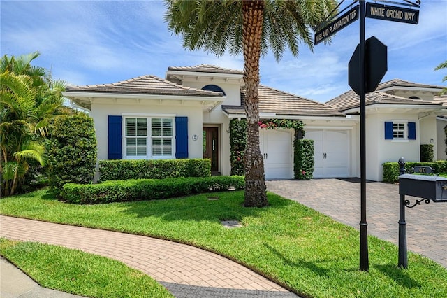 40 White Orchid Way, Vero Beach, FL 32963 - view of front of house with an attached garage, a front yard, stucco siding, driveway, and a tile roof
