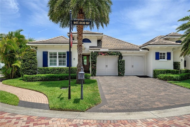 40 White Orchid Way, Vero Beach, FL 32963 - view of front of house with an attached garage, decorative driveway, stucco siding, a front lawn, and a tile roof