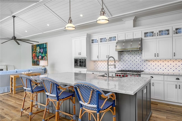 40 White Orchid Way, Vero Beach, FL 32963 - kitchen featuring a sink, built in microwave, wood finished floors, decorative backsplash, and exhaust hood