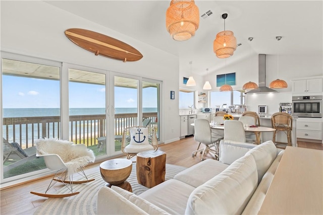 living room with light hardwood / wood-style flooring, a water view, and a healthy amount of sunlight