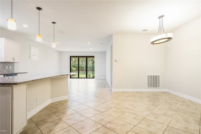 kitchen featuring white cabinetry, backsplash, dark stone countertops, pendant lighting, and light tile patterned floors