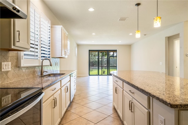 kitchen with light stone countertops, backsplash, sink, exhaust hood, and a kitchen island