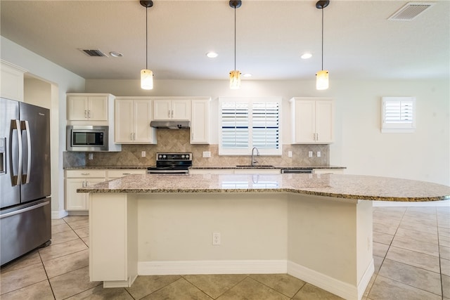 kitchen featuring a center island, pendant lighting, decorative backsplash, white cabinets, and appliances with stainless steel finishes