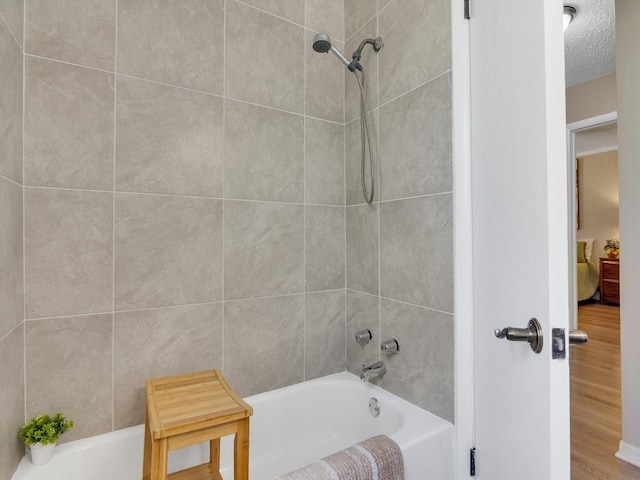 full bath with  shower combination, a textured ceiling, and wood finished floors