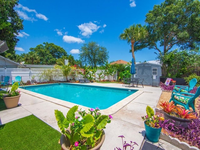 view of swimming pool featuring a patio area, a fenced in pool, an outdoor structure, a fenced backyard, and a storage unit