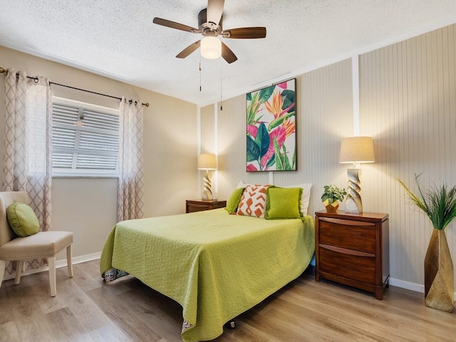 bedroom featuring a textured ceiling, baseboards, a ceiling fan, and light wood-type flooring