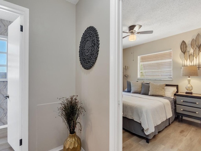 bedroom featuring a textured ceiling, ceiling fan, and light wood-style floors