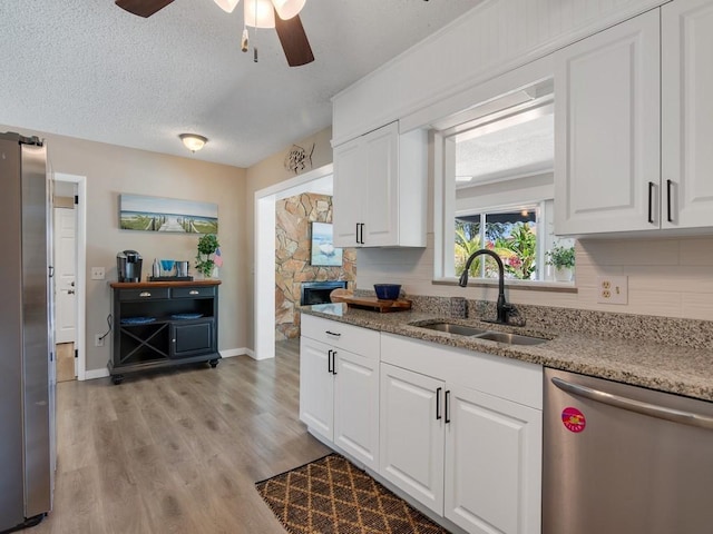 2410 53rd Ave, Vero Beach, FL 32966 - kitchen featuring stainless steel dishwasher, a sink, ceiling fan, light wood-style flooring, and white cabinets