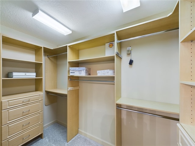 walk in closet featuring light carpet and built in desk