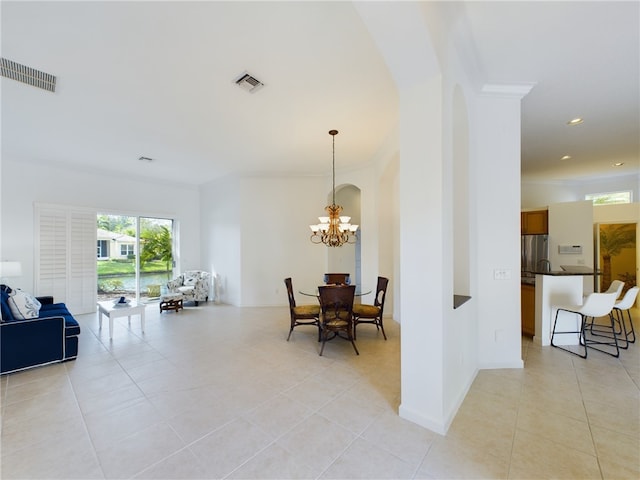 dining space featuring a chandelier, light tile patterned floors, arched walkways, visible vents, and crown molding