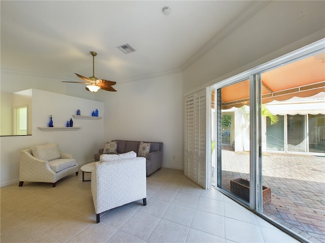 living area featuring light tile patterned floors, visible vents, ornamental molding, ceiling fan, and baseboards