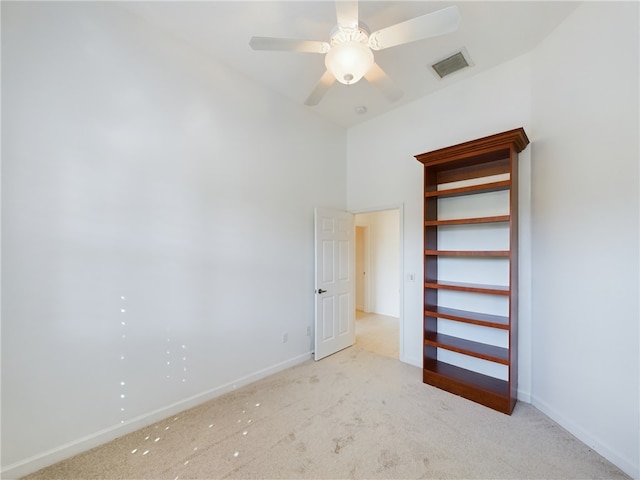 unfurnished bedroom with baseboards, visible vents, a ceiling fan, and light colored carpet