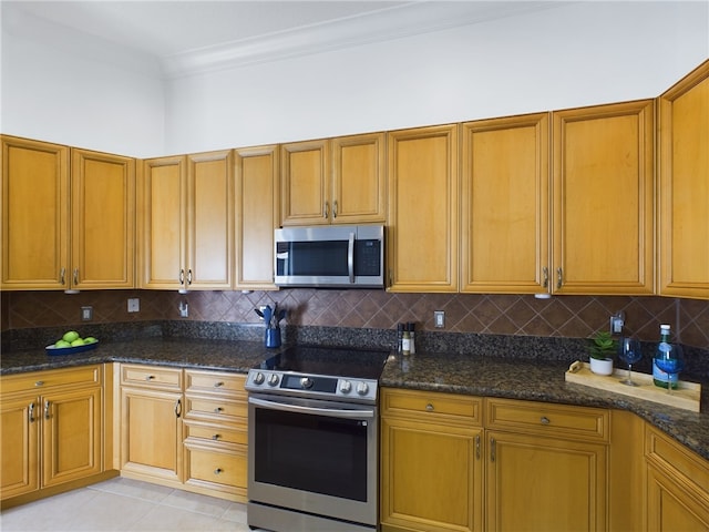 kitchen featuring dark stone counters, appliances with stainless steel finishes, ornamental molding, and tasteful backsplash