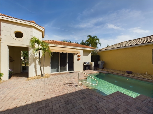 rear view of property with a tiled roof, a patio area, and stucco siding