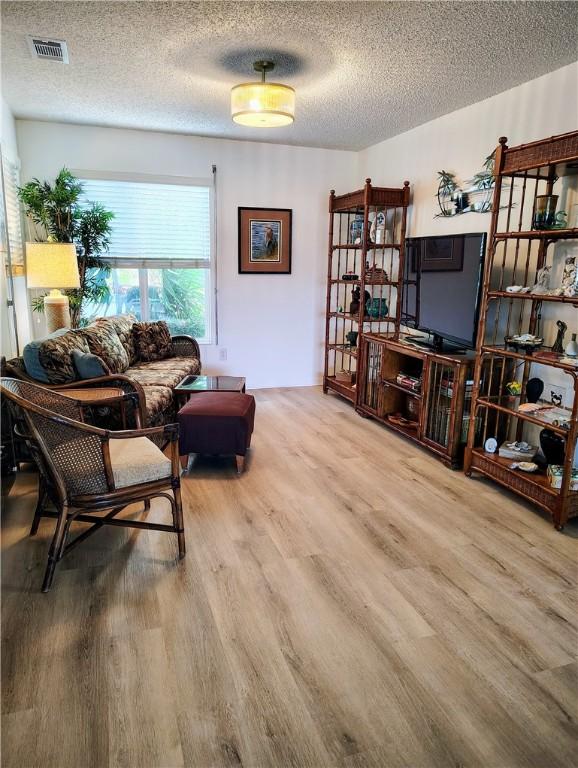 living room with a textured ceiling and light wood-type flooring