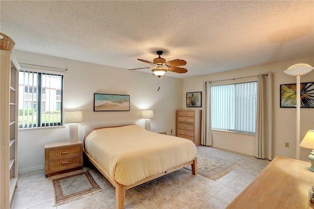 bedroom featuring ceiling fan, light tile patterned flooring, and a textured ceiling