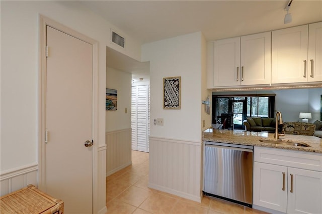 kitchen featuring sink, white cabinetry, dishwasher, light stone counters, and light tile patterned floors