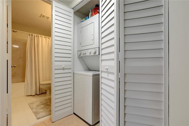 laundry area featuring stacked washer and dryer and light tile patterned floors