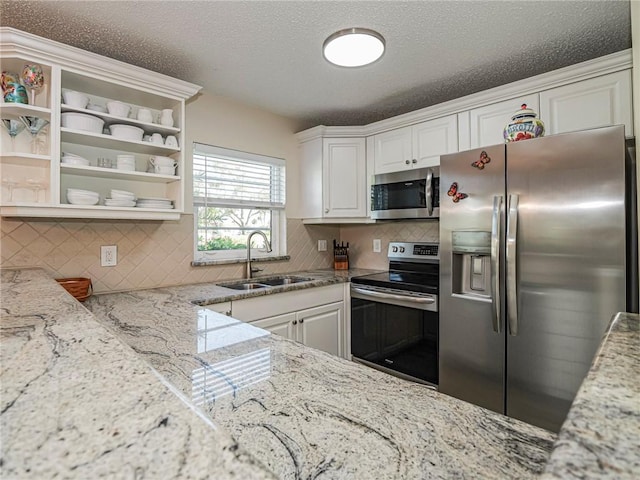 kitchen featuring sink, light stone counters, a textured ceiling, white cabinets, and appliances with stainless steel finishes