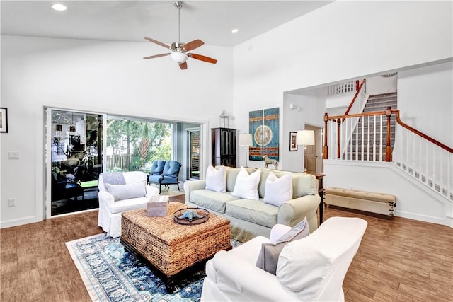 living room featuring ceiling fan, wood-type flooring, and a high ceiling