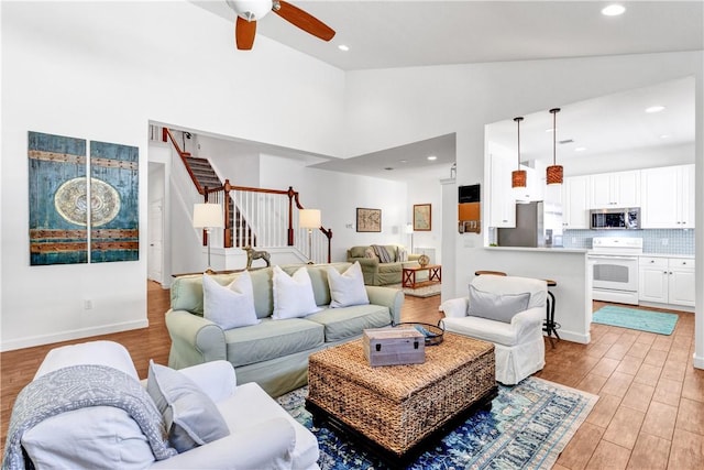 living room with ceiling fan, light hardwood / wood-style flooring, and high vaulted ceiling