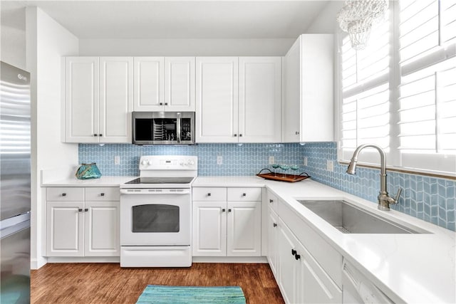 kitchen featuring plenty of natural light, dark wood-type flooring, stainless steel appliances, sink, and white cabinetry