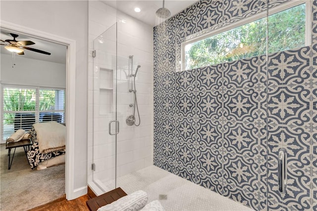 bathroom featuring ceiling fan, a healthy amount of sunlight, and a shower with door